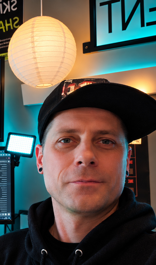 Joshua Hale wearing a black cap in his cyan-lit office